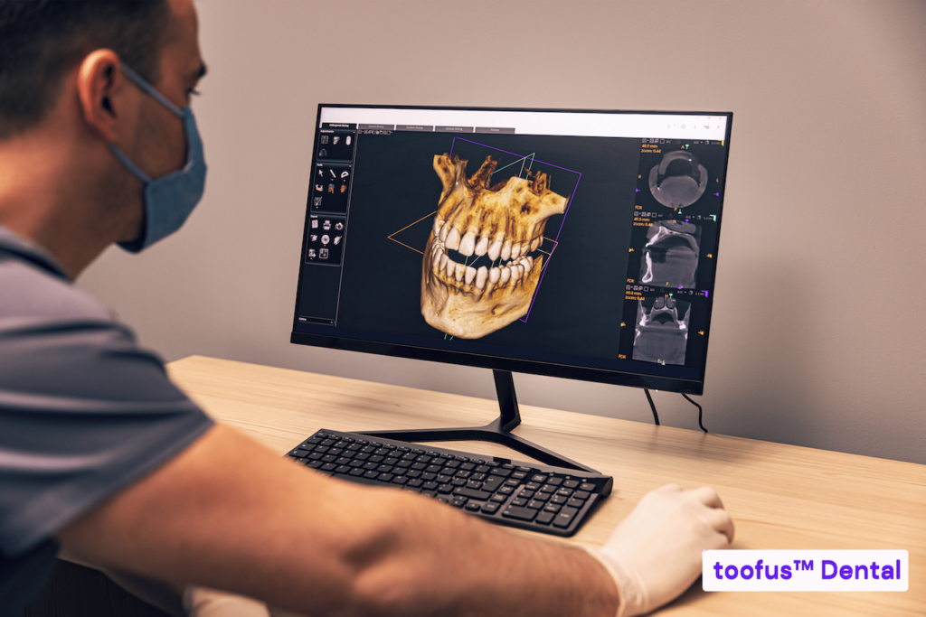 The Essential Guide: Stop Hidden Costs for Dental Implants 3 Dentist looking at a 3D dental scan on the computer - toofus™ Dental